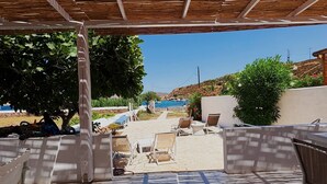 Un patio al aire libre con vista al mar, suelo de piedra y mobiliario exterior.