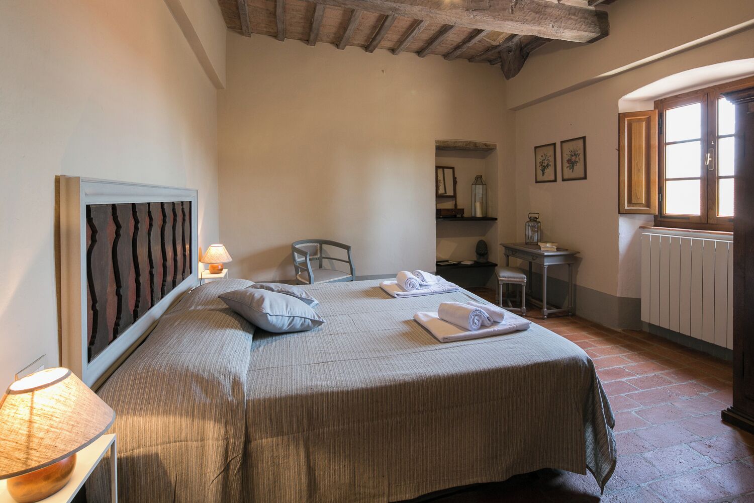 Ein Schlafzimmer mit Bett, Stuhl, Schreibtisch, Lampe und Fenster.