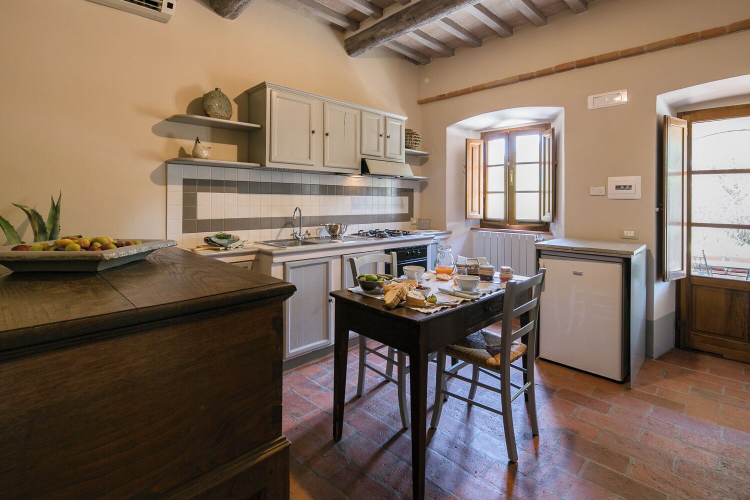 A compact kitchen with a wooden island, white cabinets, and a small refrigerator.