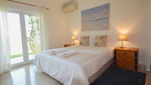 Een slaapkamer met een bed, twee nachtkastjes met lampen, een schilderij aan de muur en uitzicht door het raam.