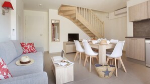 Ein modernes Wohnzimmer mit Sofa, Esstisch, Stühlen, einer Treppe und einer Küchenzeile.