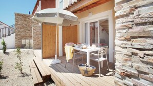 Eine Terrasse mit Tisch, Stühlen, einem Sonnenschirm und einer Steinmauer.