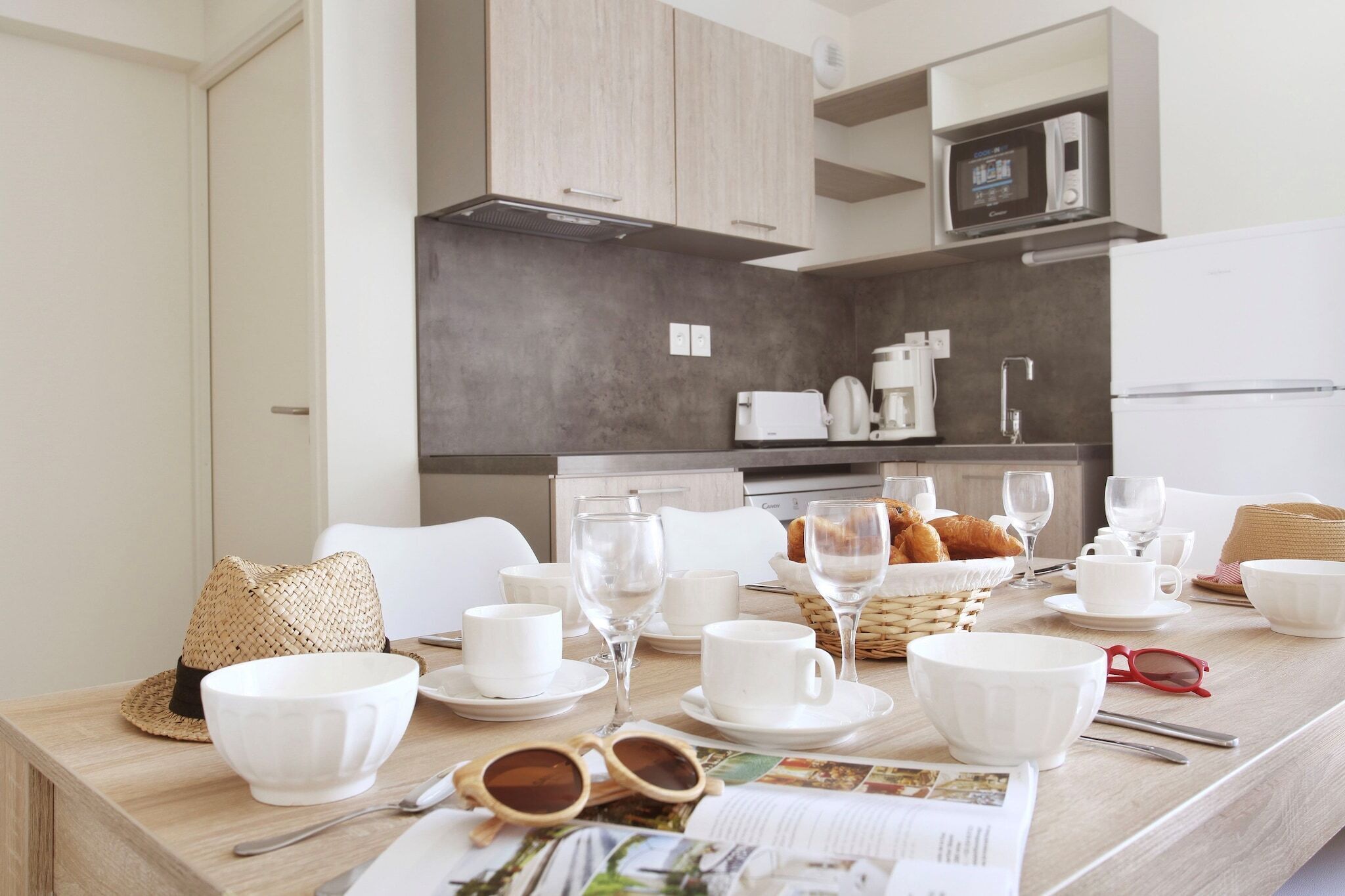 Une cuisine moderne avec des meubles blancs, une machine à café et un four à micro-ondes.