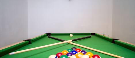 Et poolbord med dartskive og et sæt billardkugler.