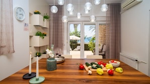 A modern dining area with a wooden table, hanging glass pendant lights, and a view of the outdoors.