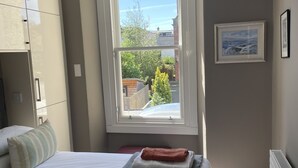 Een slaapkamer met een groot bed, een raam met uitzicht, een radiator en een lijst met een afbeelding aan de muur.