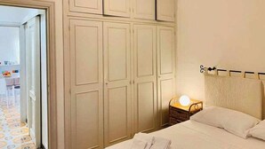 A bedroom with a bed, a nightstand with a lamp, and a wardrobe. - Beachfront three room apartment with garden "Ostrica" (Alghero)