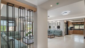 A spacious living area with a sectional sofa, a coffee table, and a glass partition with metal frames. -  Elaida Villa, Refined Group Escape • Pool & Play (Rethymno)