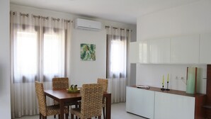 A dining area with a wooden table and wicker chairs, a white cabinet with a mirror, and a painting on the wall. - IL VILLINO --- SWIMMING POOL NOT SHARED AND PRIVATE BEACH --- (Cefalù)