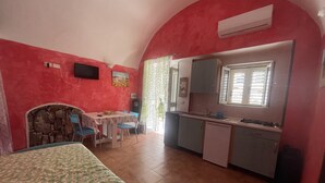 A compact room with a bed, a small dining table, and a kitchenette. -  House in the nineteenth-century village  (Vieste)