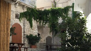 A courtyard with stone walls, wooden benches, and potted plants. -  House in the nineteenth-century village  (Vieste)