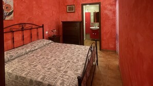 A bedroom with a bed, a nightstand, a dresser, and a bathroom visible through an open door. -  House in the nineteenth-century village  (Vieste)