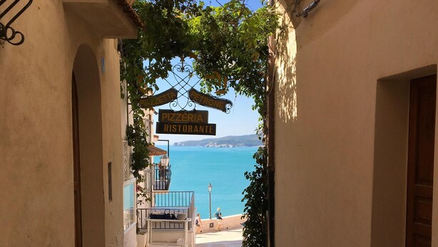 A narrow alleyway with a stone archway leading to a beach. -  House in the nineteenth-century village  (Vieste)
