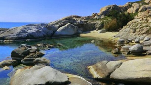 Une plage rocheuse avec une eau claire et de gros rochers.