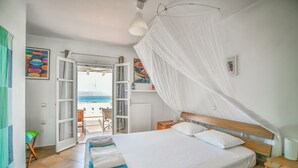 Une chambre à coucher avec un lit, une table de chevet, une fenêtre avec des rideaux et une vue sur la mer.