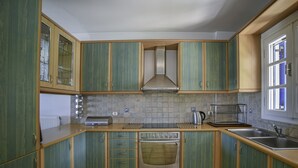 Une cuisine avec des meubles de couleur verte, un four en acier inoxydable, un grille-pain et un évier.