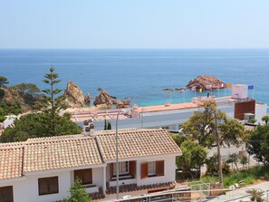 A coastal building with a tiled roof, a balcony, and a view of the sea.
