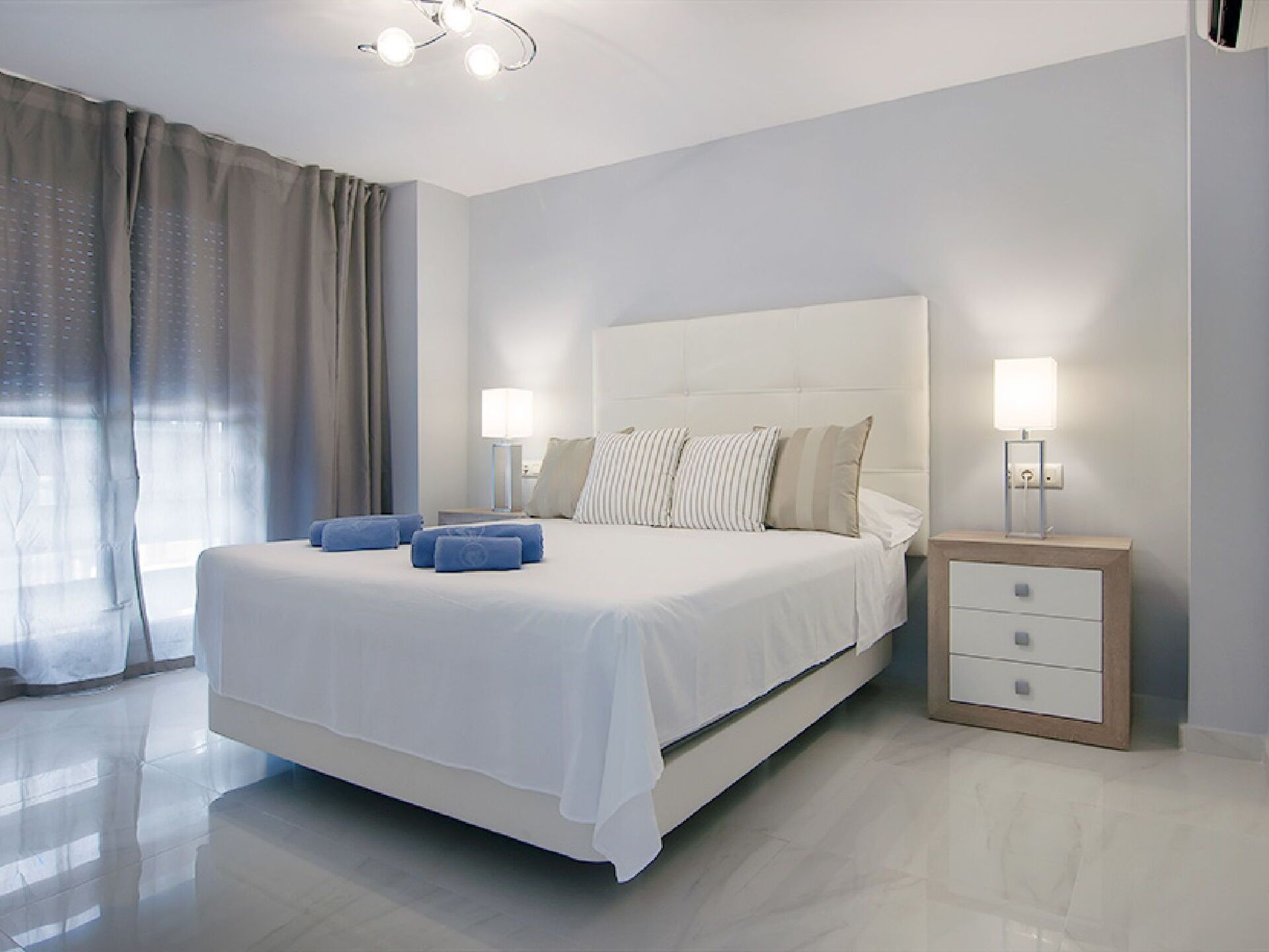 Une chambre moderne avec un grand lit, deux tables de chevet et une petite table d’appoint.