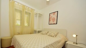 A bedroom with a bed, bedside table, and a nightstand. - Cosy apartment for 5 people with WIFI, A/C, pool, TV, terrace and pets allowed (Solin)