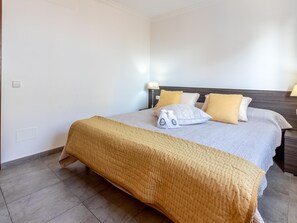 A hotel room with a bed, a bedside table, a lamp, and a wall socket. - Apartamento Castello Playa · Your beachfront apartment in Can Picafort. (Can Picafort)