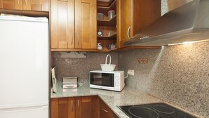 A kitchen with wooden cabinets, a microwave, a toaster, and a stove. - NEW APARTMENT CLOSE TO THE BEACH 2 (Tossa de Mar)