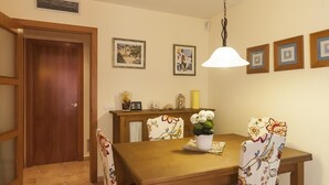 A dining area with a wooden table and chairs, a hanging light fixture, and framed artwork on the wall. - NEW APARTMENT CLOSE TO THE BEACH 2 (Tossa de Mar)