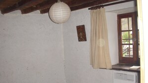 Een kamer met een bed, een raam met gordijn, een aan de muur hangend schilderij en een radiator.