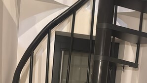 A black spiral staircase with multiple steps and handrails, leading to a landing area with a door. - Charming and modern vintage style apartment located in prime location! (Antwerpen)