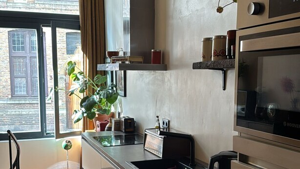 A modern kitchen with a large window, a built-in oven, and a countertop with various appliances. - Charming and modern vintage style apartment located in prime location! (Antwerpen)