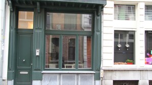 A green building with a large window and a door. - Charming and modern vintage style apartment located in prime location! (Antwerpen)