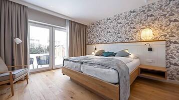 Ein Schlafzimmer mit einem großen Bett, einem Sessel, einem Balkon und einer Wand mit Muster.