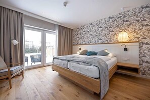 A bedroom with a large bed, a chair, a balcony, and a patterned wall.