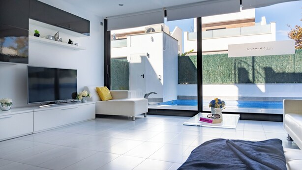 A modern living room with a flat-screen TV, white sofas, a coffee table, and a view of a swimming pool. - Luxury Villa Pool, 10 mins Walk to Beach & Golf near by (San Pedro del Pinatar)