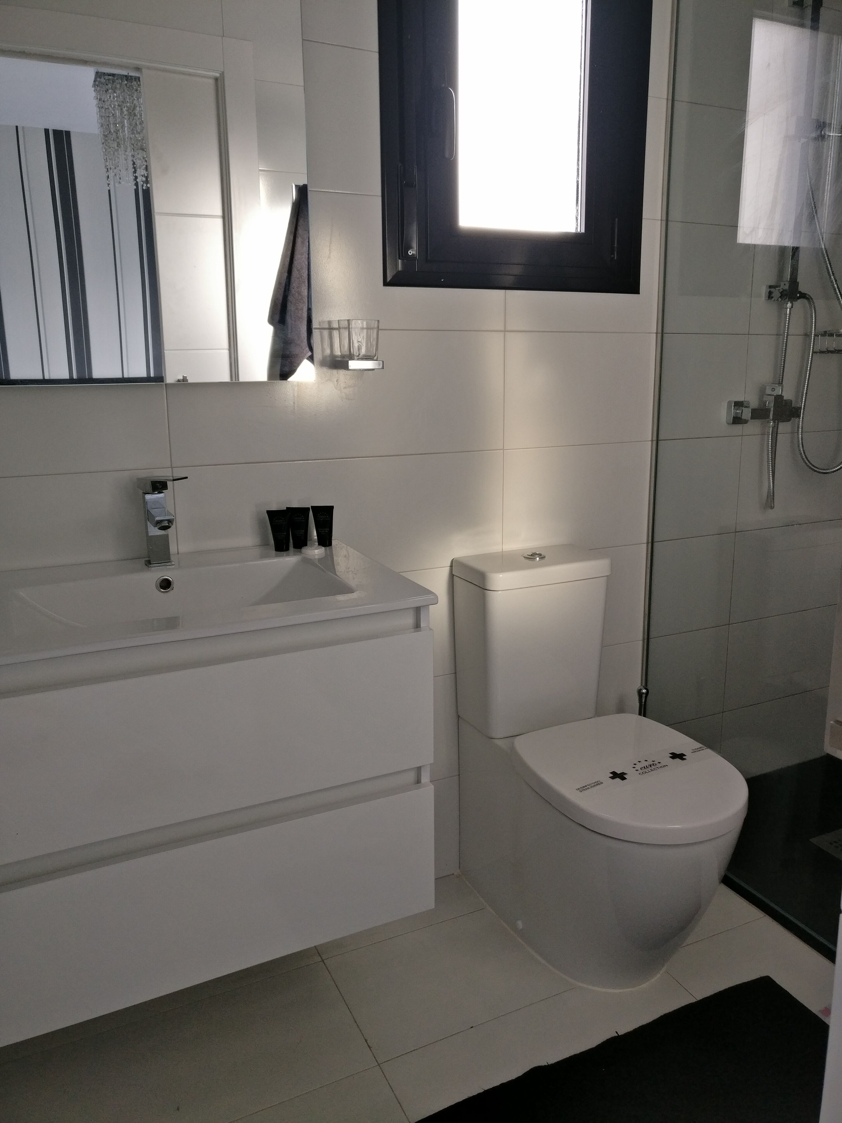 Ein modernes Badezimmer mit Waschbecken, Toilette und Dusche, alles in Weiß.