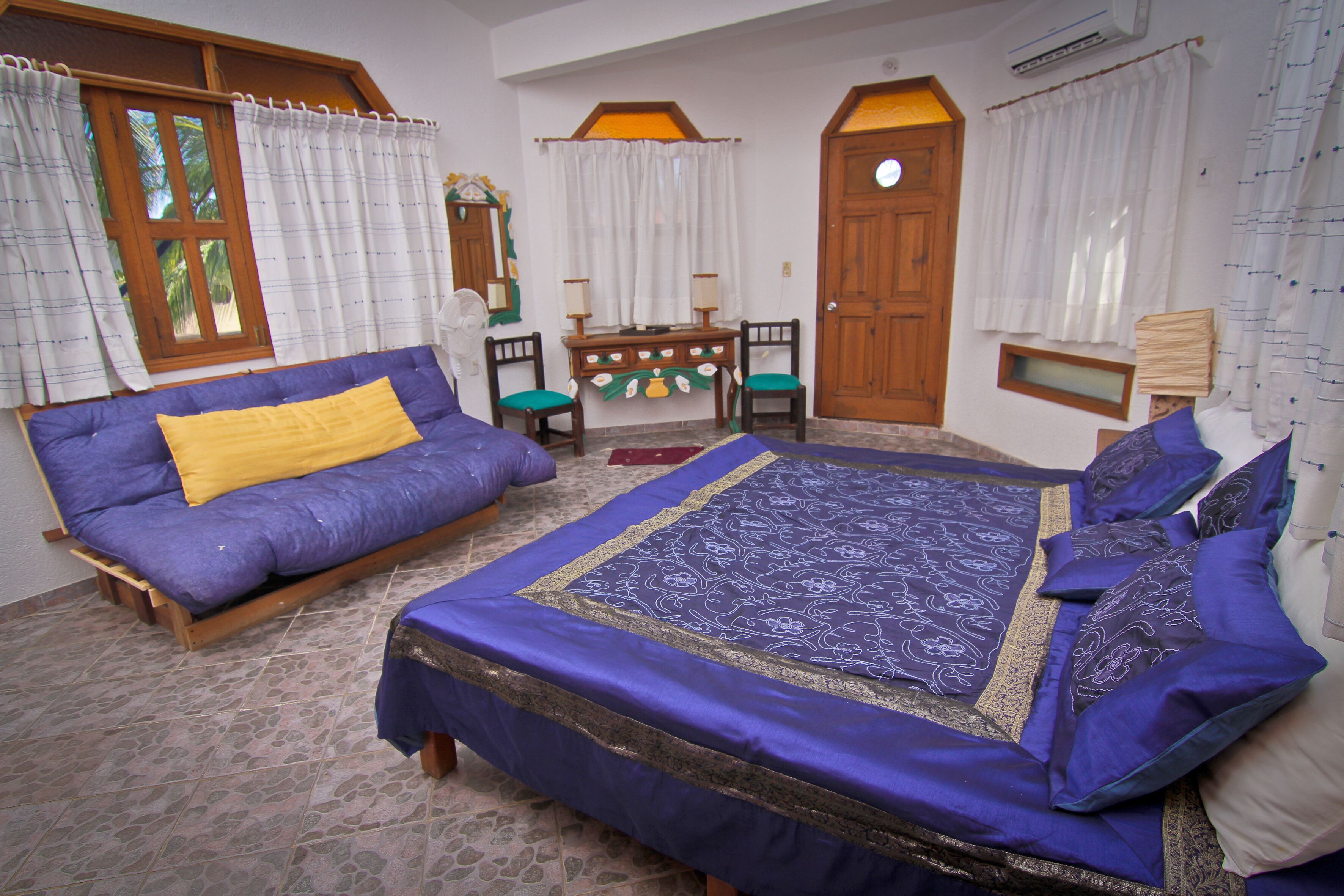 A room with a bed, a sofa, a desk, and a chair.