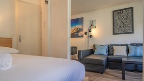 Une chambre d’hôtel avec un lit, un canapé, un plancher en bois et un mur orné d’un tableau et d’une citation.