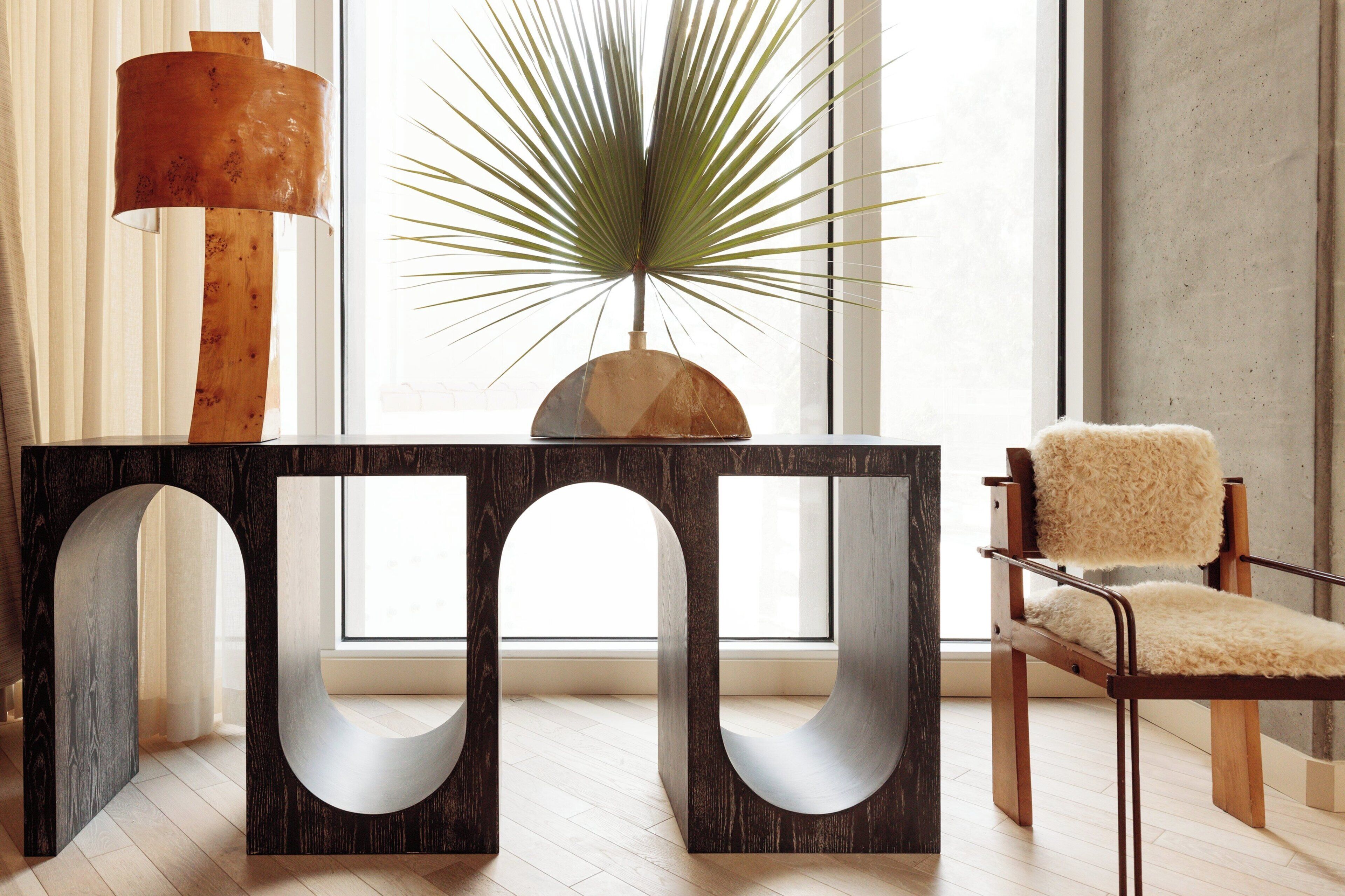 A modern interior with a wooden table, a potted plant, and a fluffy chair.