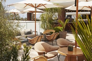 An outdoor patio area with multiple seating arrangements, including chairs and tables, surrounded by umbrellas and potted plants. - Santa Monica Proper Hotel, a Member of Design Hotels (Santa Monica)