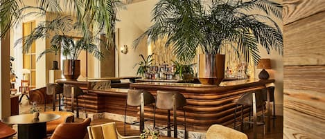 A cozy bar area with wooden furniture, a bar counter, and large potted plants.