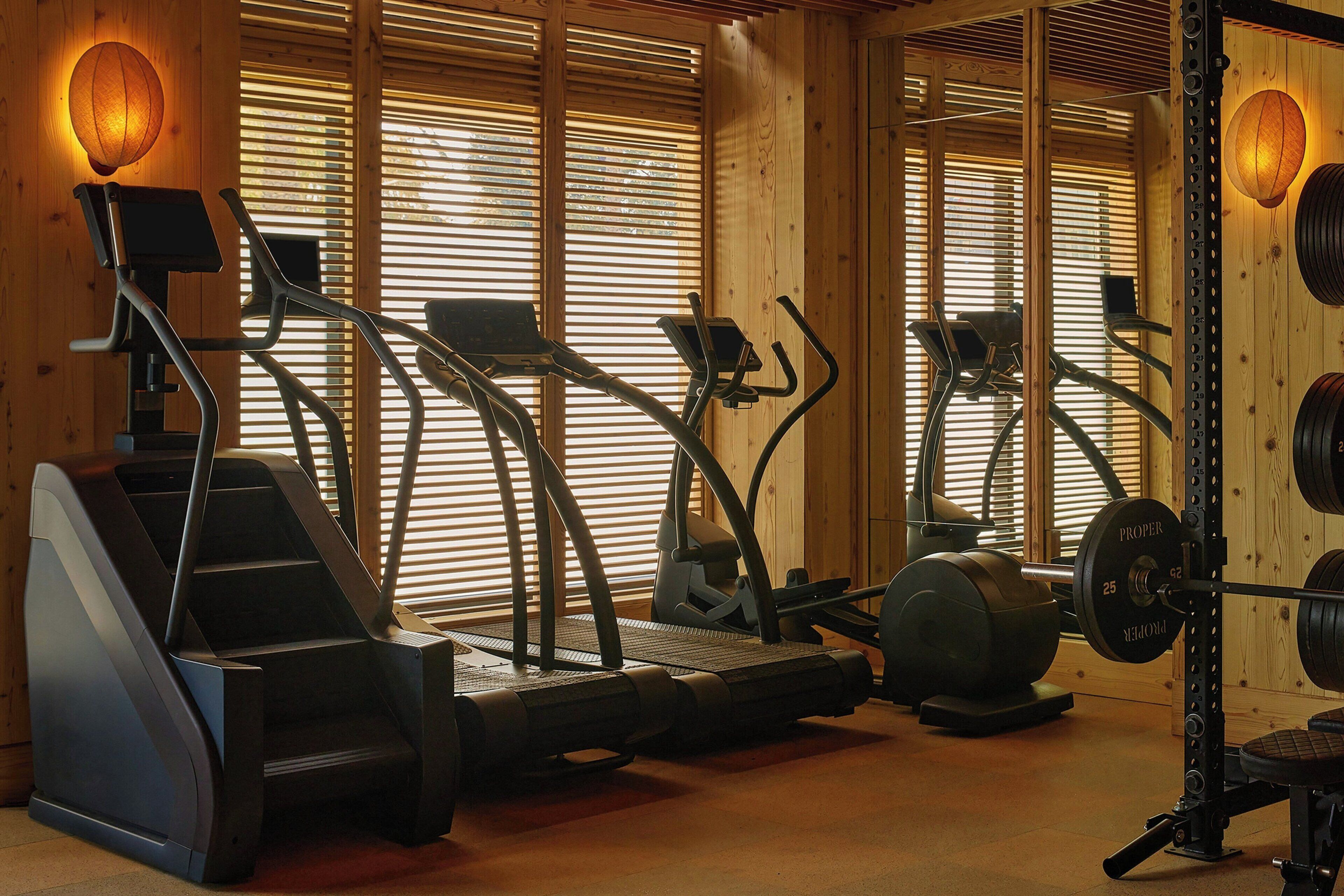 A gym with exercise equipment including treadmills, elliptical machines, and a weight bench.