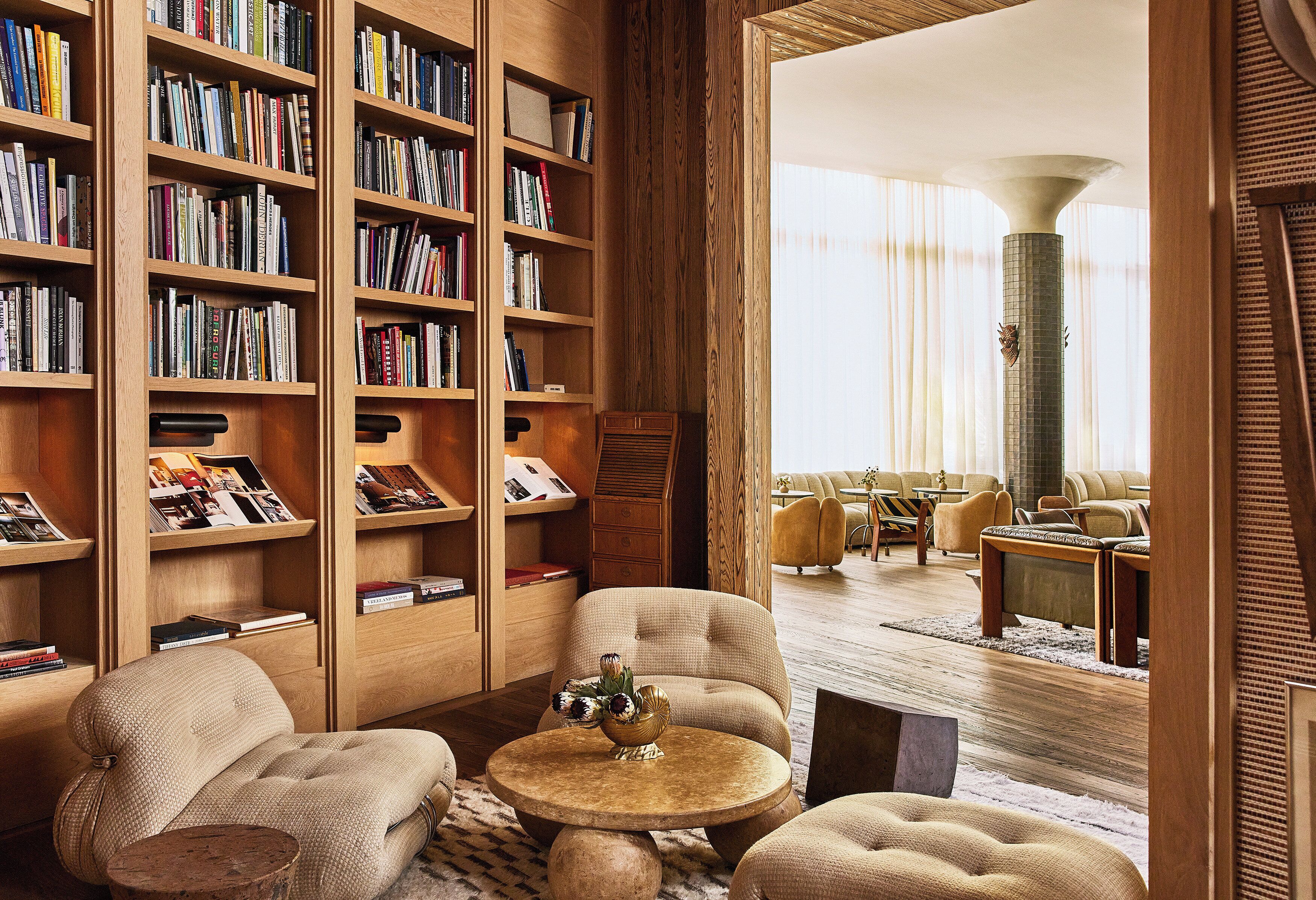 Un salon chaleureux avec une grande bibliothèque, des sièges confortables et une vue sur une autre pièce.