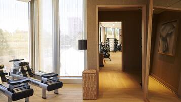 Une salle de sport équipée de matériel d’exercice, dotée de grandes fenêtres et d’un plancher en bois.