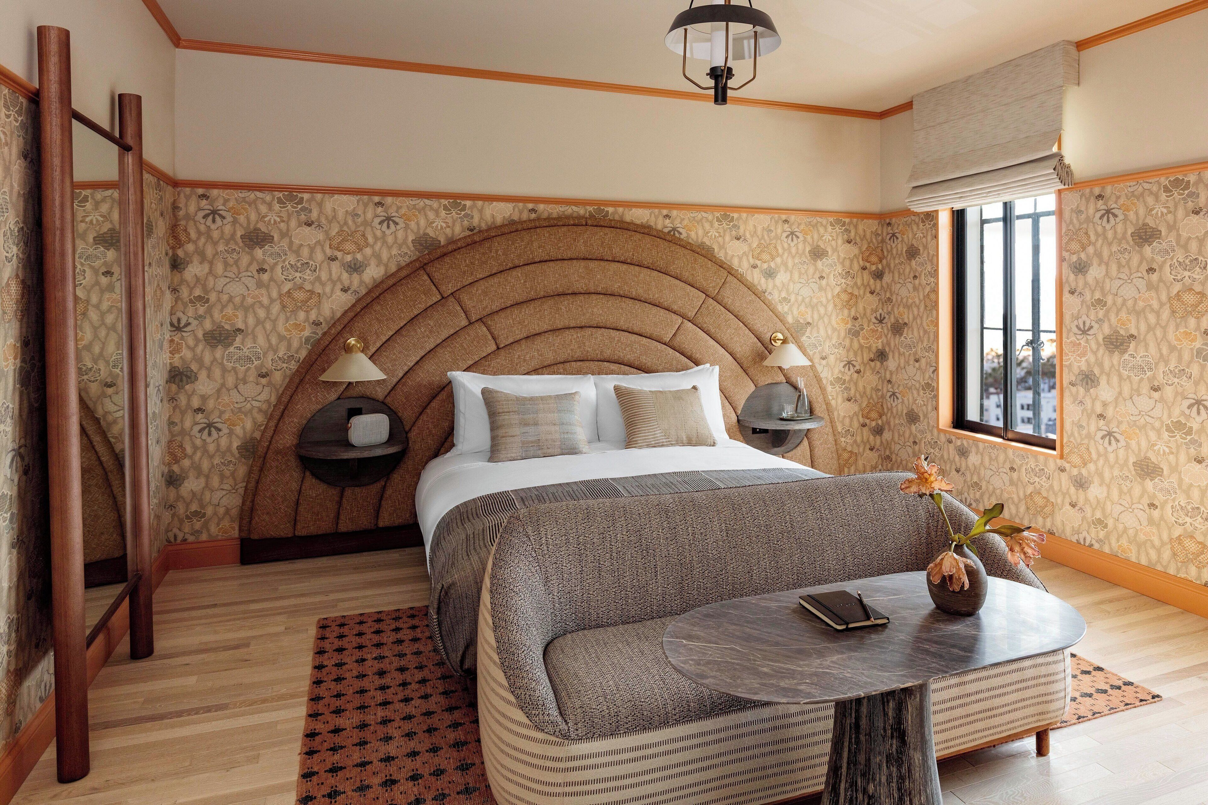 A bedroom with a large bed, a round table, a nightstand, and a window.