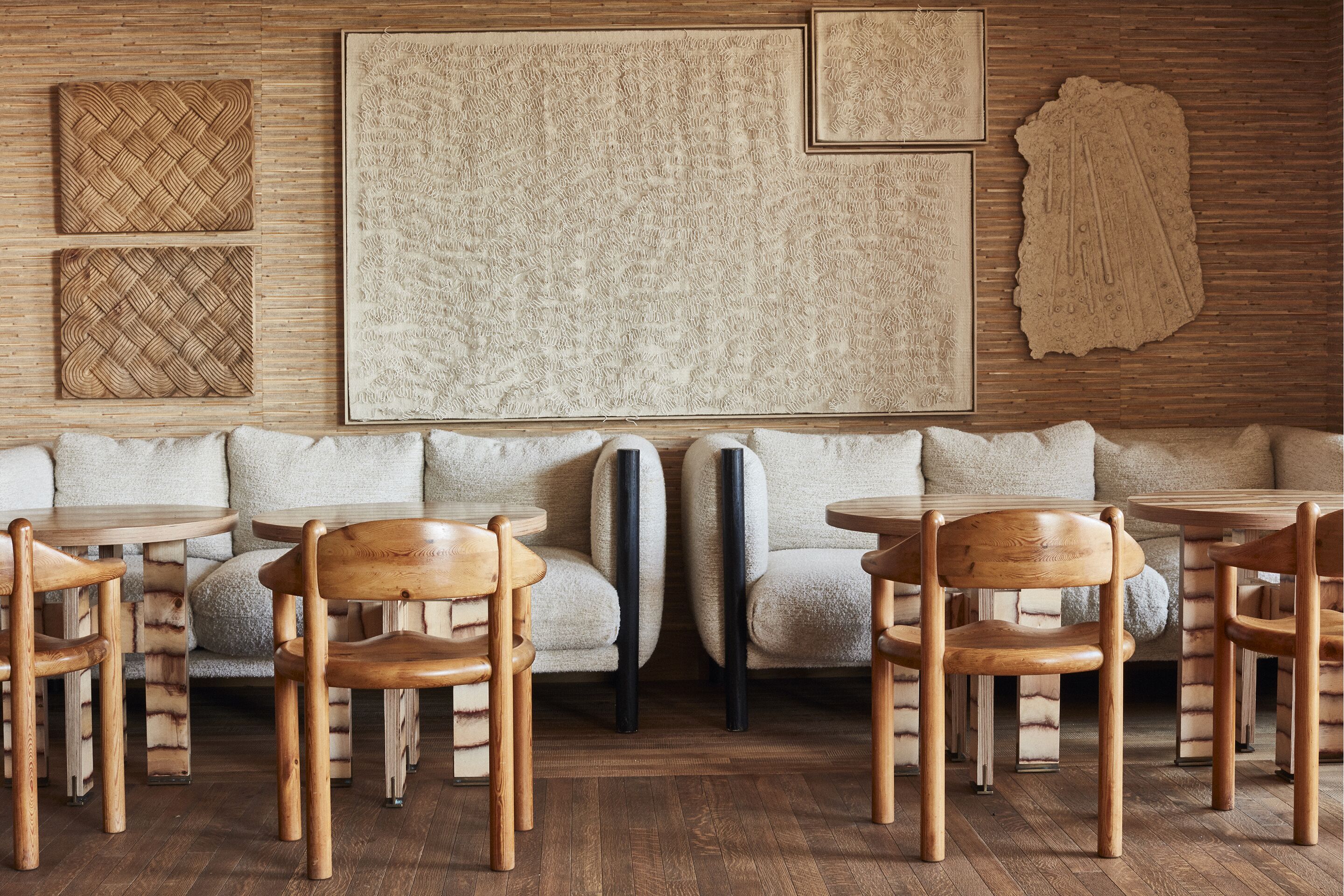 A modern interior with a wooden floor, a sofa set, and a large abstract artwork on the wall.