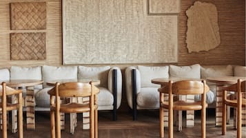 A modern interior with a wooden floor, a sofa set, and a large abstract artwork on the wall.