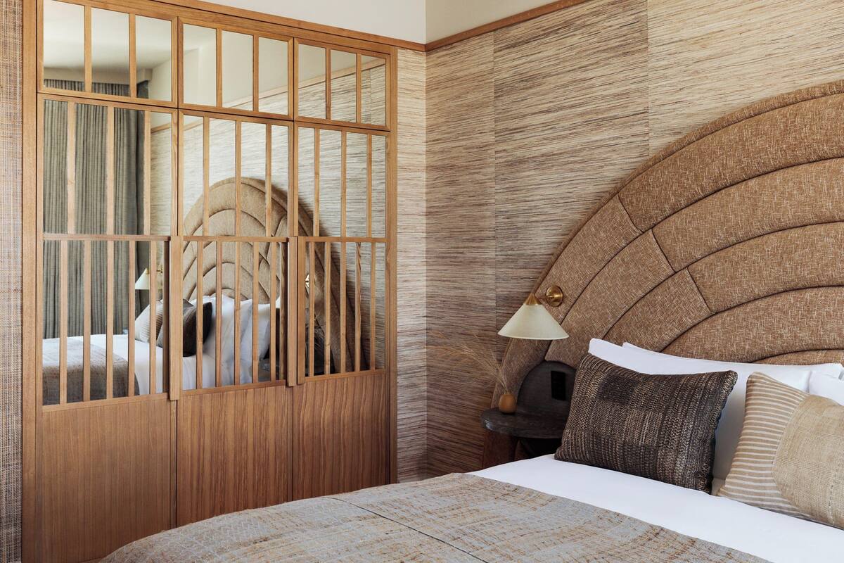 Un dormitorio con un armario de madera, un cabecero de diseño curvo y una lámpara de noche.