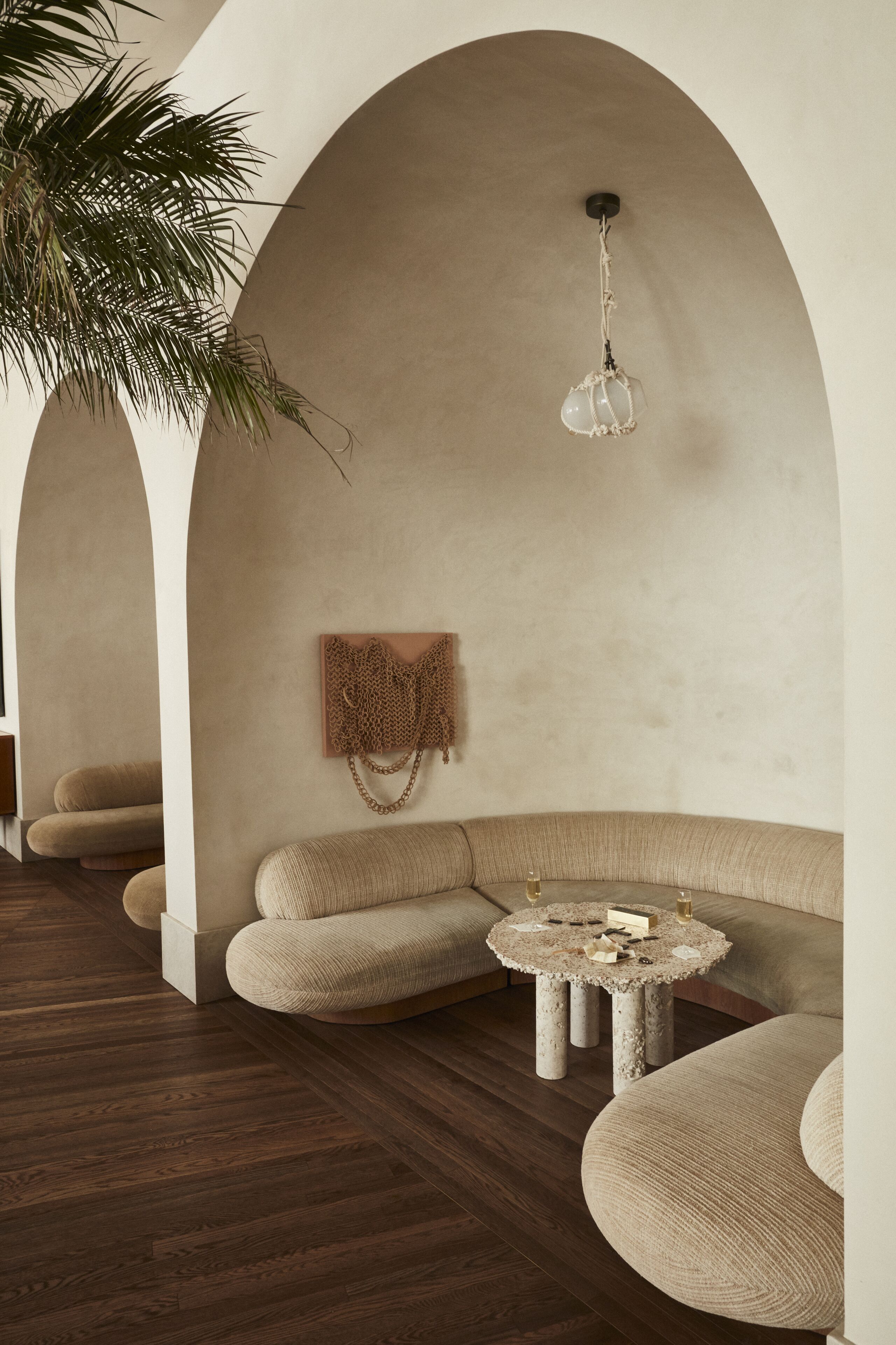 A modern interior with a curved sofa, a small round table, and a hanging light fixture.