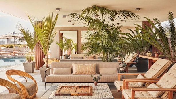 A sunlit indoor space with a pool, lounge chairs, a sofa, and various potted plants. - Santa Monica Proper Hotel, a Member of Design Hotels (Santa Monica)
