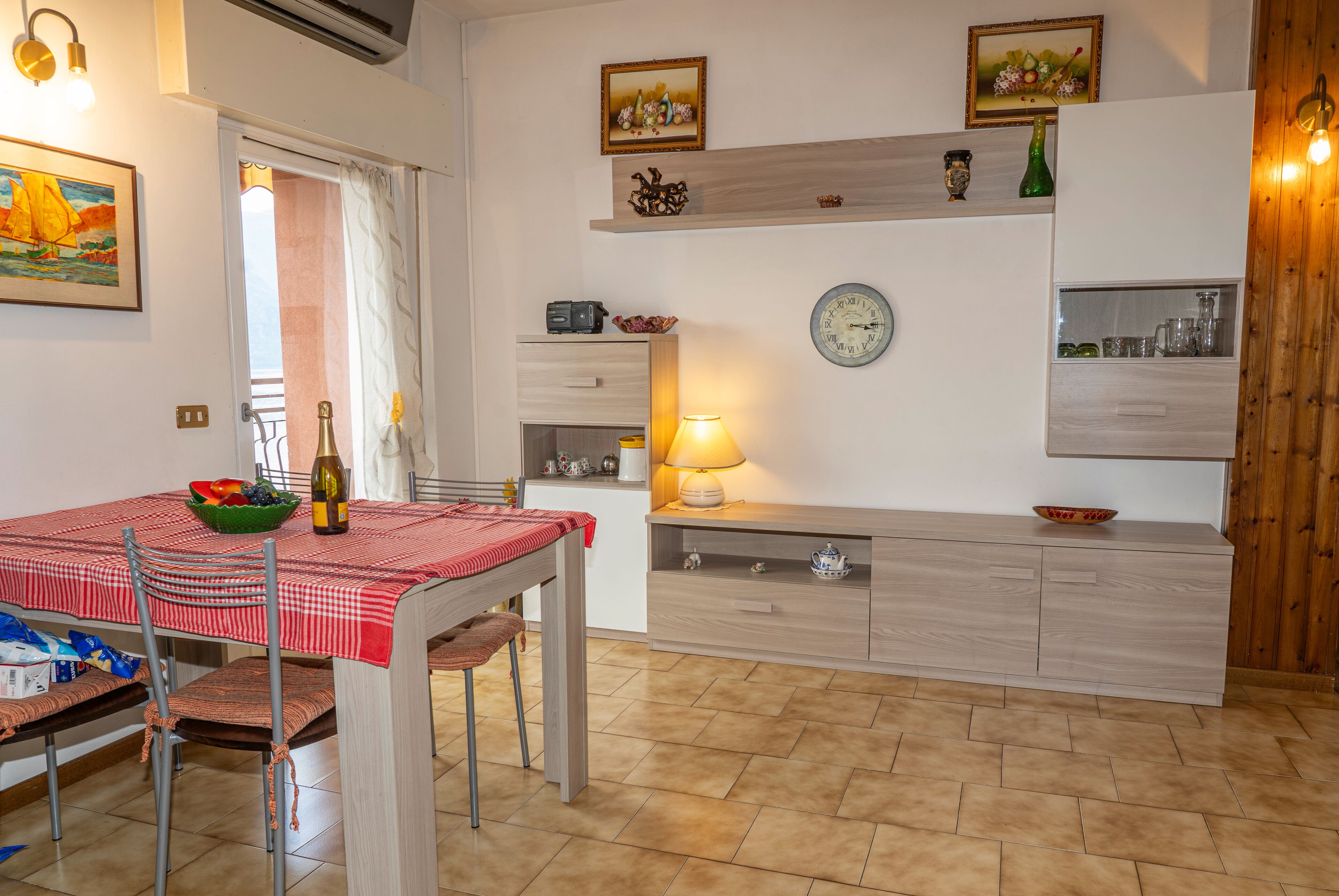 A kitchen with a dining table, chairs, a clock, and a cabinet.