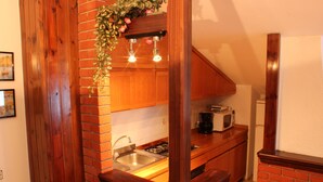 Une cuisine avec un mur recouvert de briques, des armoires en bois, un évier en acier inoxydable et un four à micro-ondes posé sur le plan de travail.